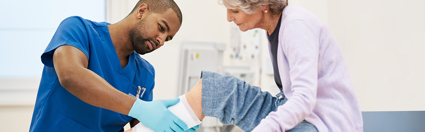 A male nurse exchanging the dressing of a patient. A male nurse exchanging the dressing of a patient.